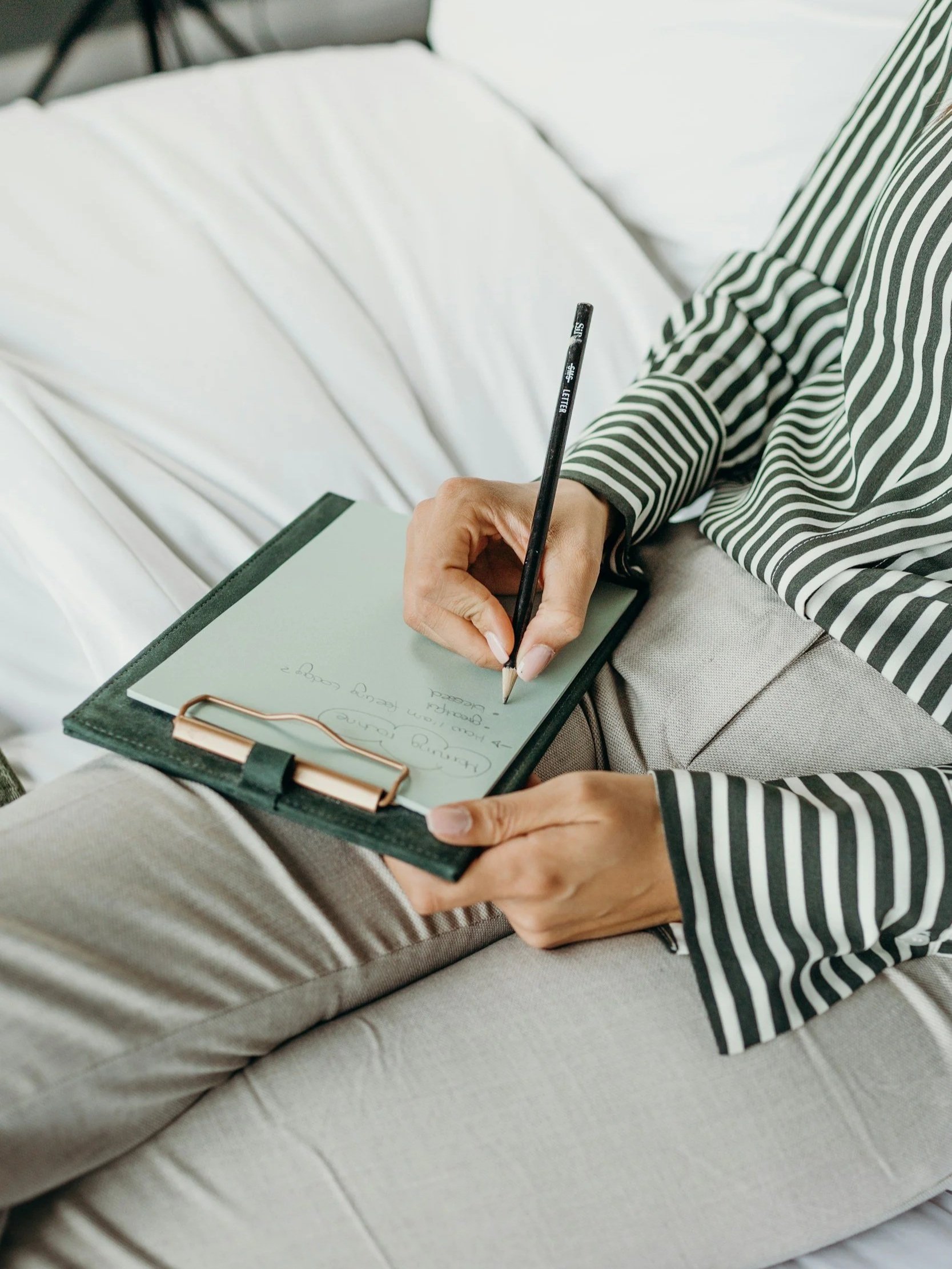 A close up image of a person's hands taking notes on a clipboard.