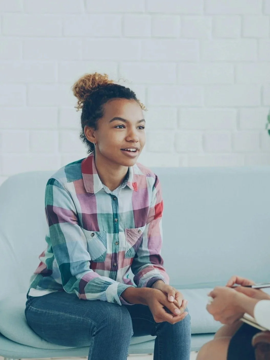 A woman sitting on a couch talking to someone holding a clipboard and taking notes