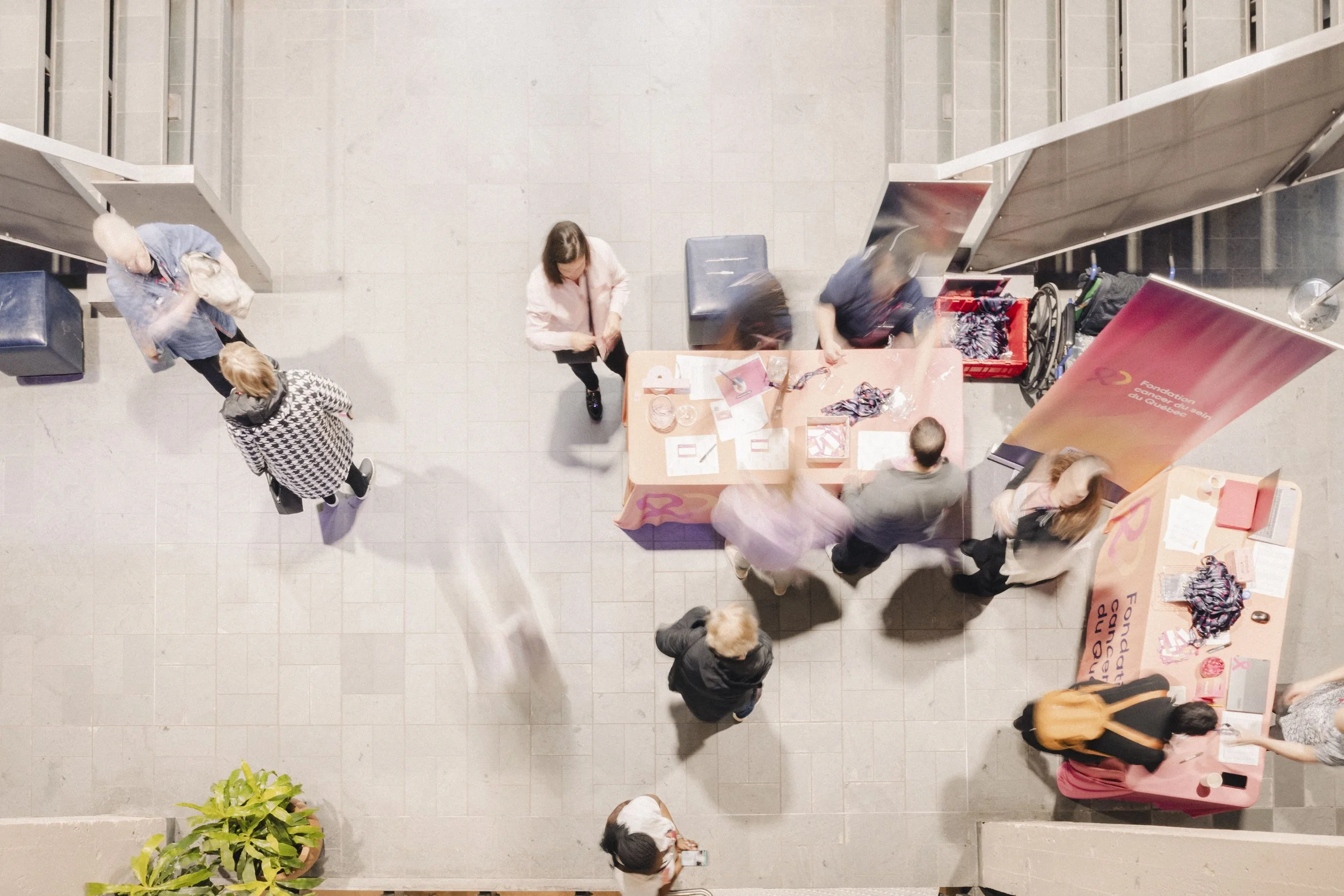 Overhead view of people at a table with informational material, in a public indoor space, with a banner for foundation fundraising.