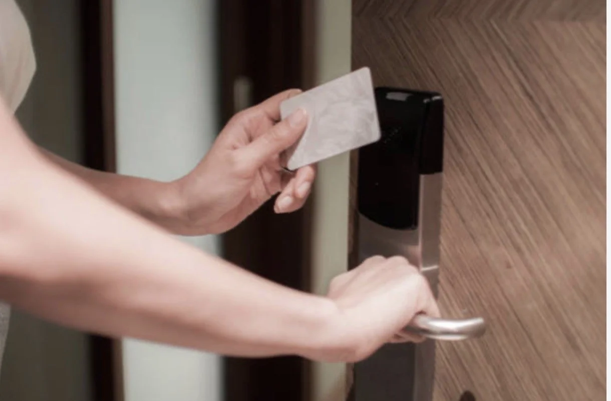 Person holding a key card near a door lock to unlock it.