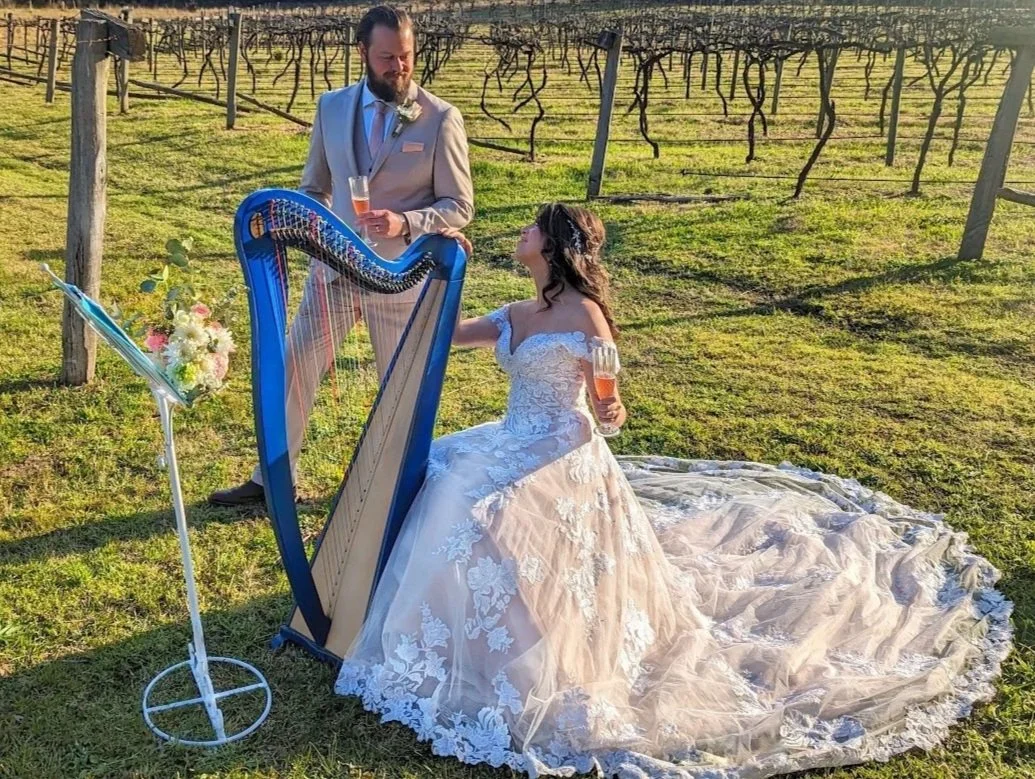 Newlyweds beside a blue lever harp at a vineyard wedding