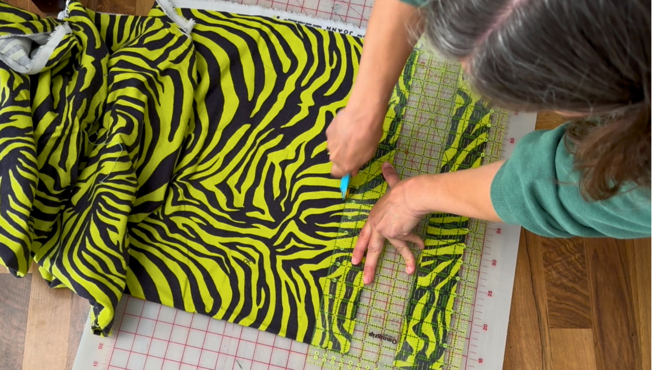 cutting bright yellow and black flannel fabric into 2.25 inch strips for the batting