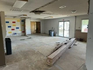 Interior of a room under renovation with construction materials, including wooden planks, scattered on the floor, and walls partially painted.