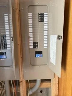 An electrical breaker panel with its door open, showing circuit breakers inside.