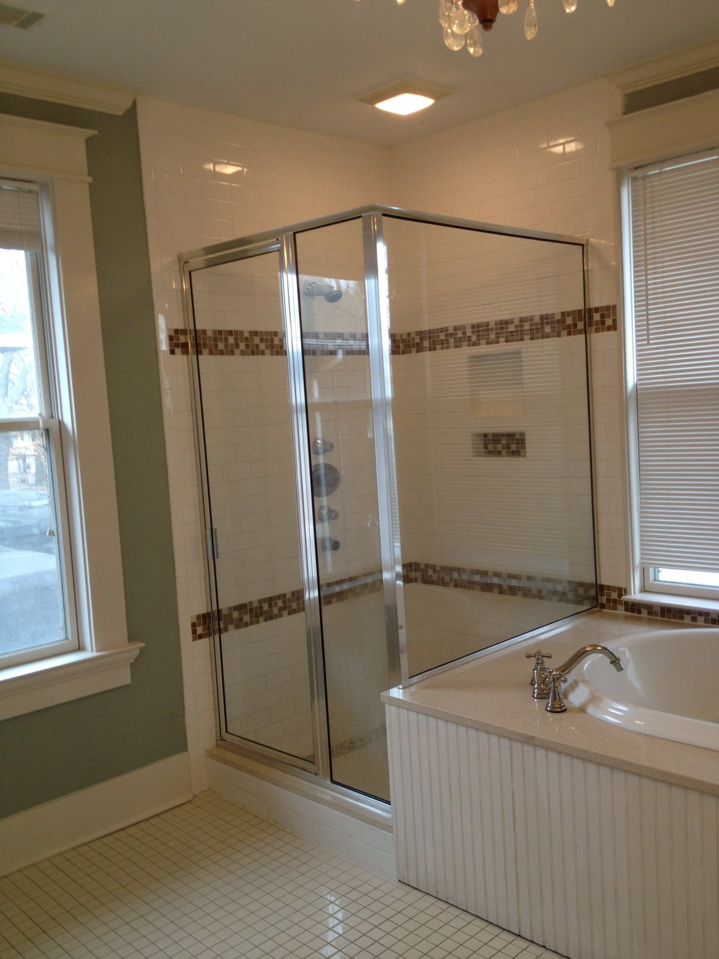 Bathroom with a glass enclosed shower, a bathtub with a chrome faucet, a window with blinds, and a ceiling light fixture.