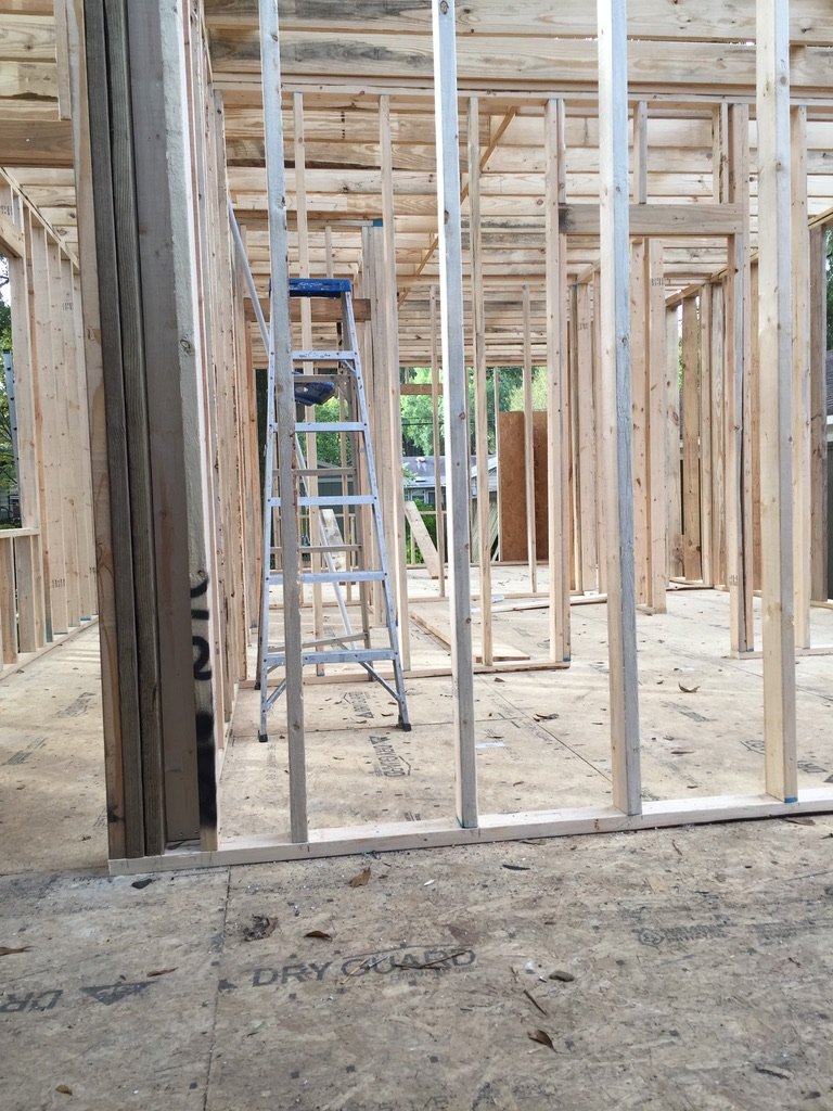 Interior of a house under construction with wooden framing and a ladder.
