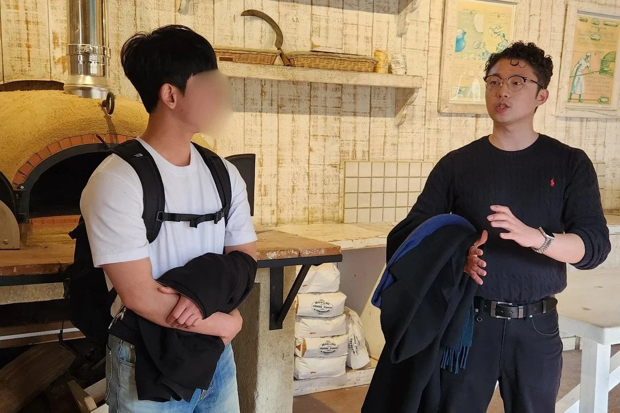 Jonghyuk and a man from the Andong delegation are visiting the educational farm. They are looking at each other and seem to be deep in conversation.