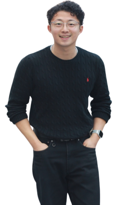 Smiling young man wearing glasses, a black sweater, and black pants.