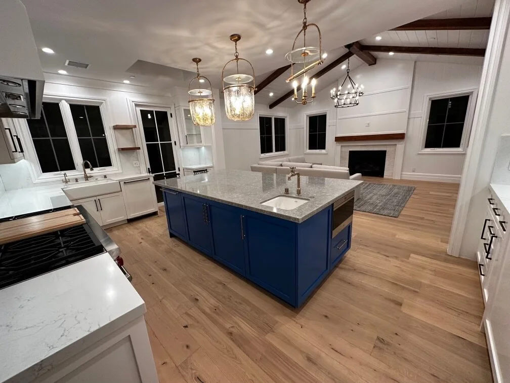[kitchen-remodeling] Custom kitchen with a blue island, marble counters and white cabinetry under a beamed vaulted ceiling in Los Angeles