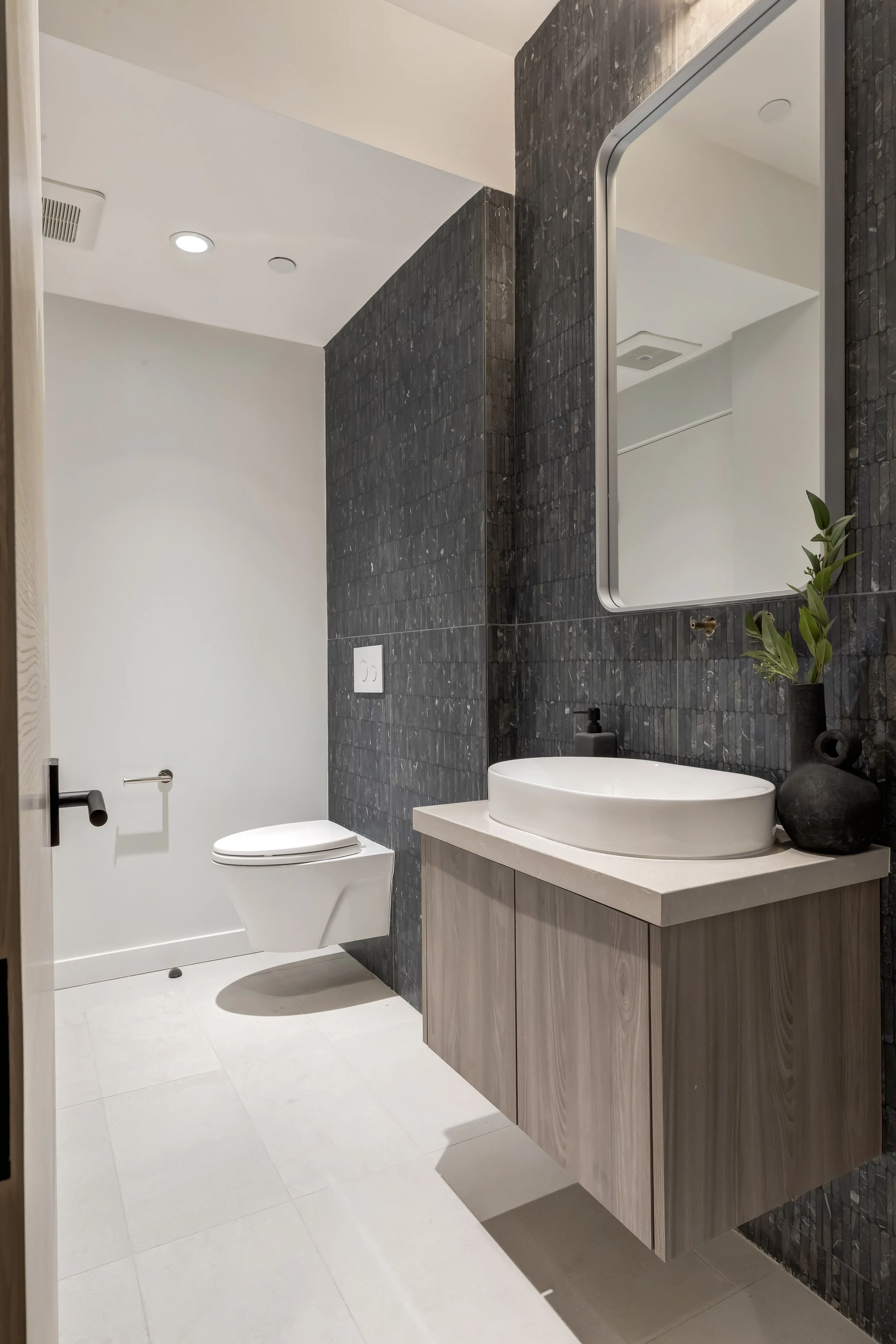 [bathroom-remodeling] Bathroom with charcoal stacked-tile feature wall, vessel sink, and wood floating vanity, Encino custom home