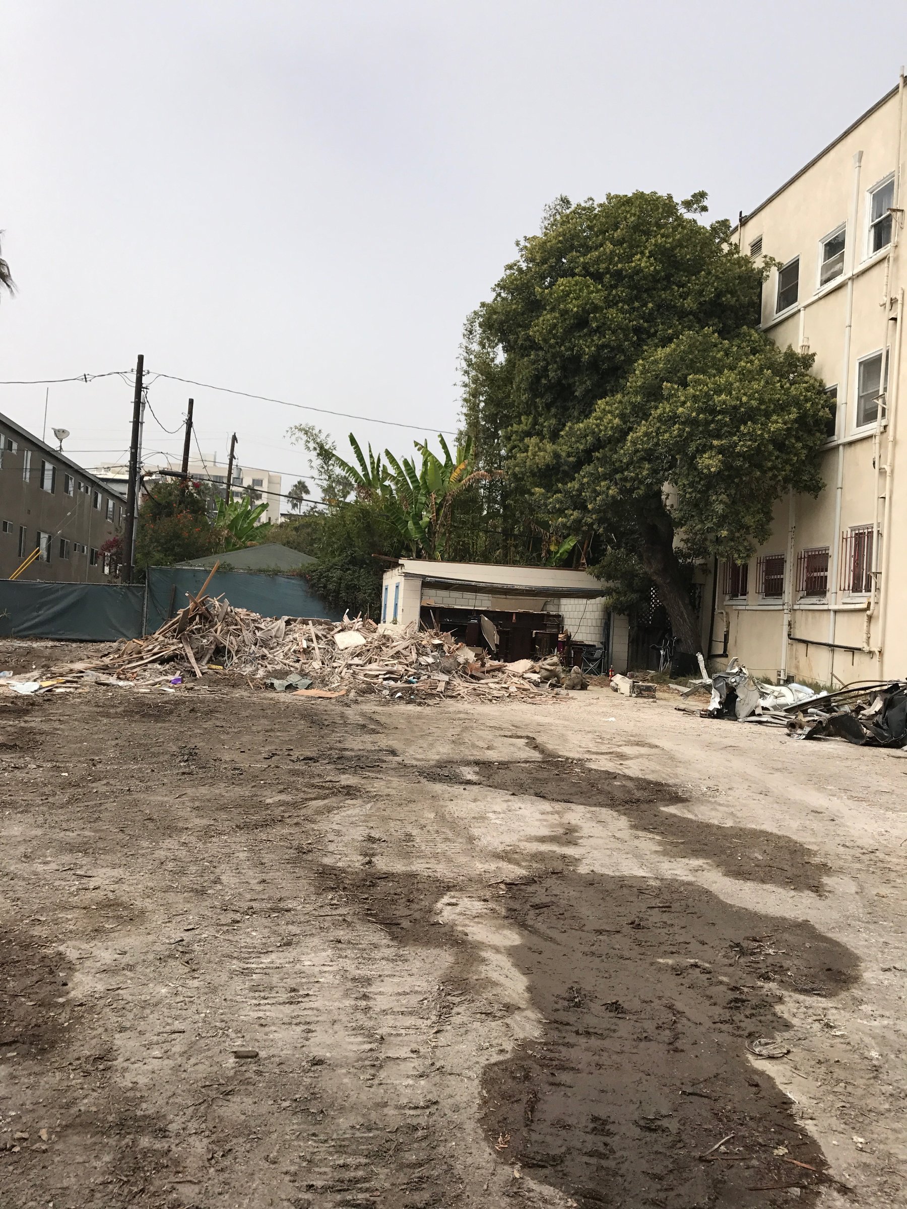 [new-construction] Cleared dirt lot with demolition debris beside a neighboring building in Santa Monica