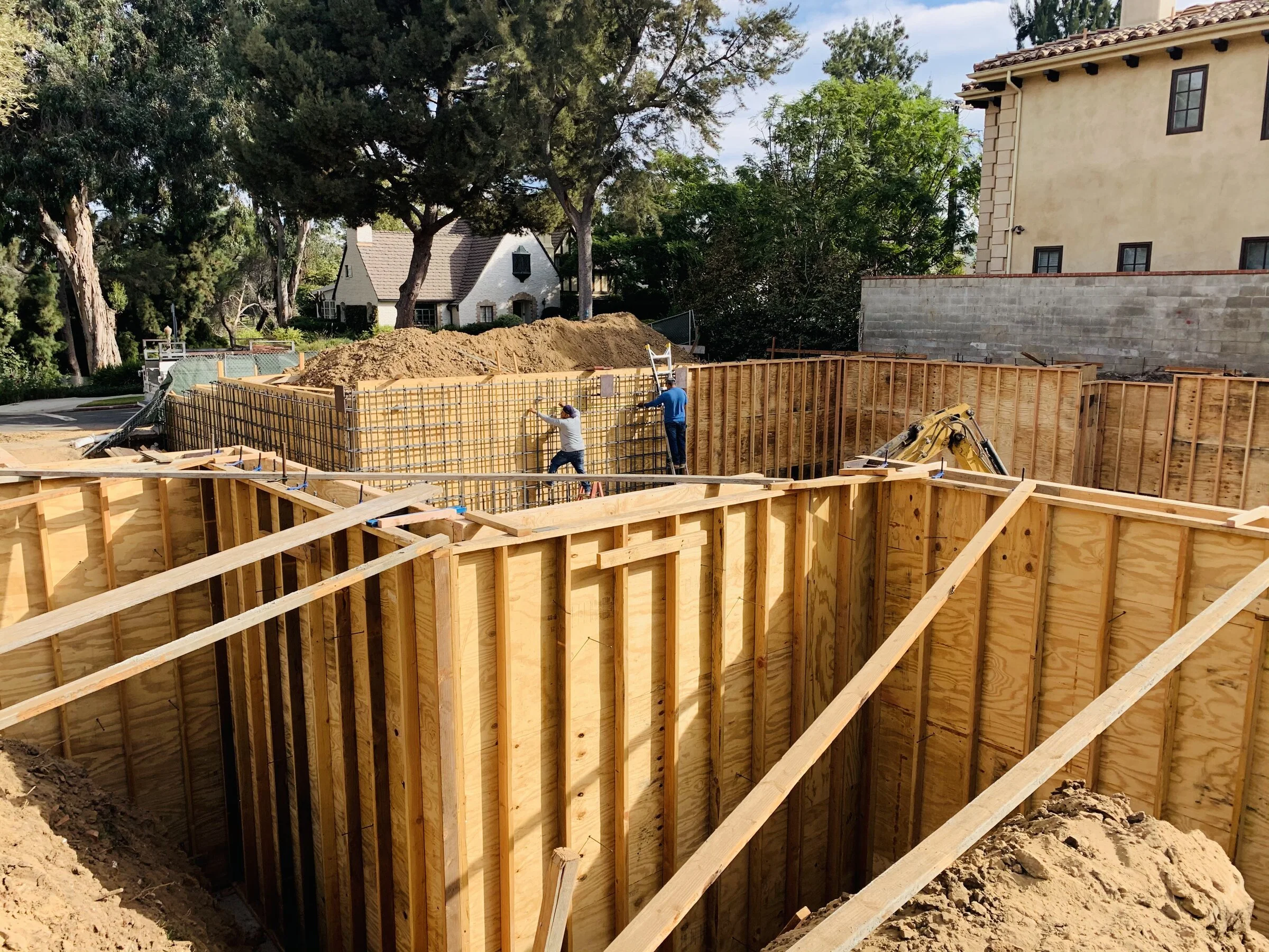 [new-construction] Basement foundation wall forms with crew tying steel in a Los Angeles residential neighborhood