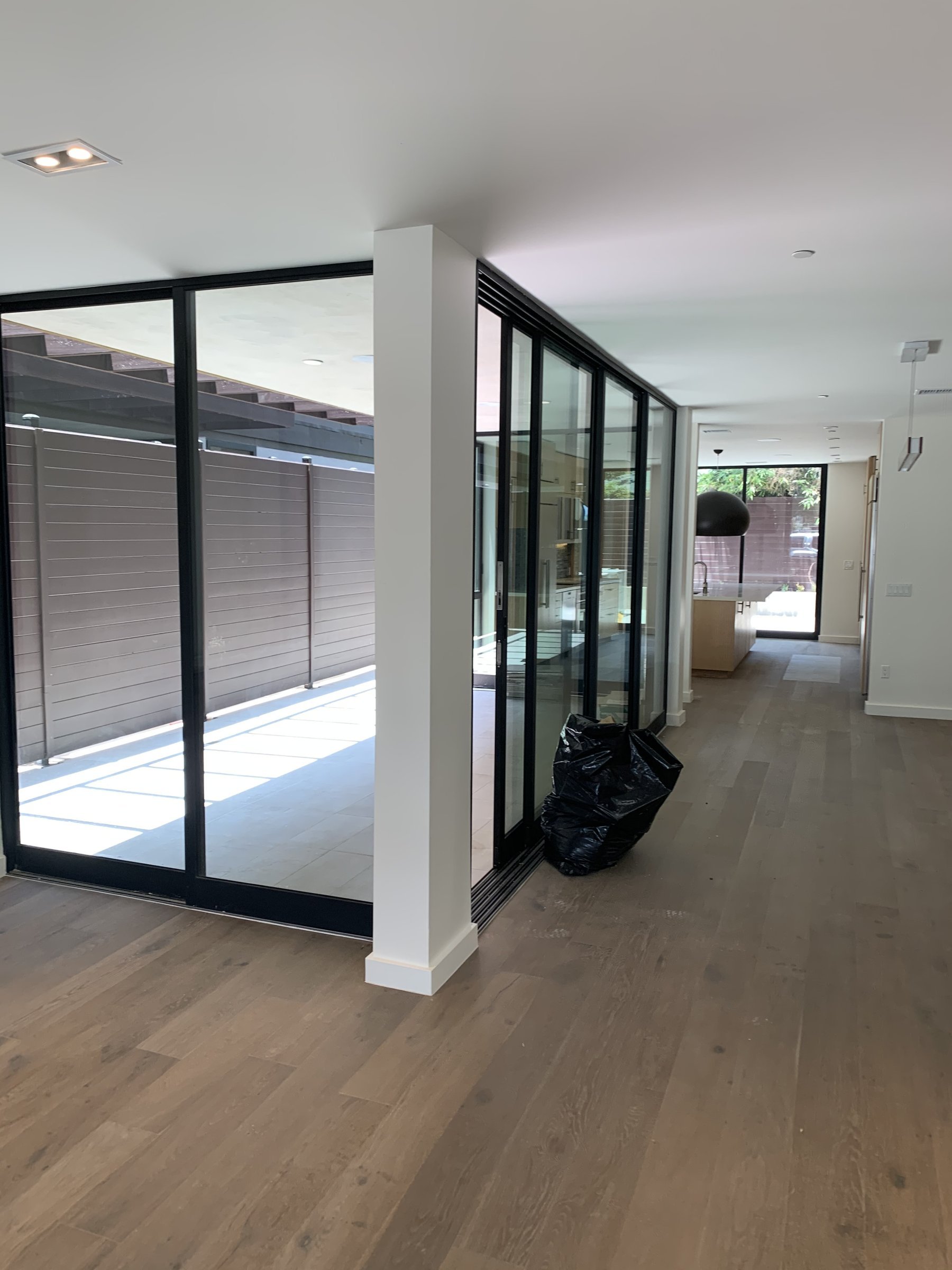 [home-additions] Modern interior with oak floors, a white column and steel-framed glass looking toward the kitchen in Santa Monica