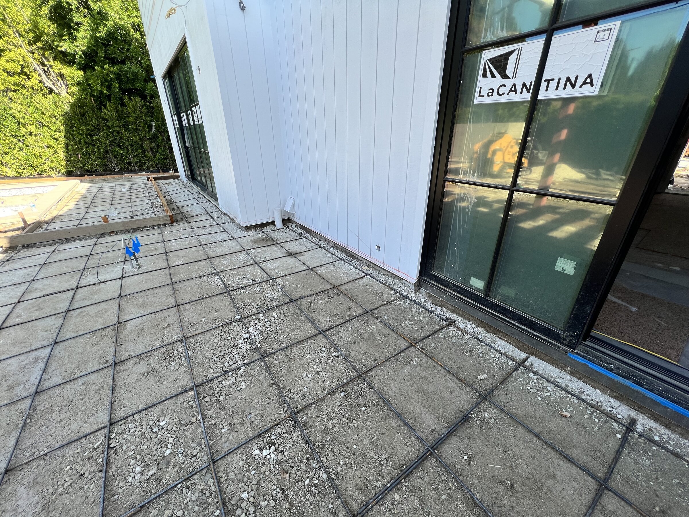 [new-construction] Rebar grid laid for a concrete patio beside folding glass doors on a Los Angeles new build