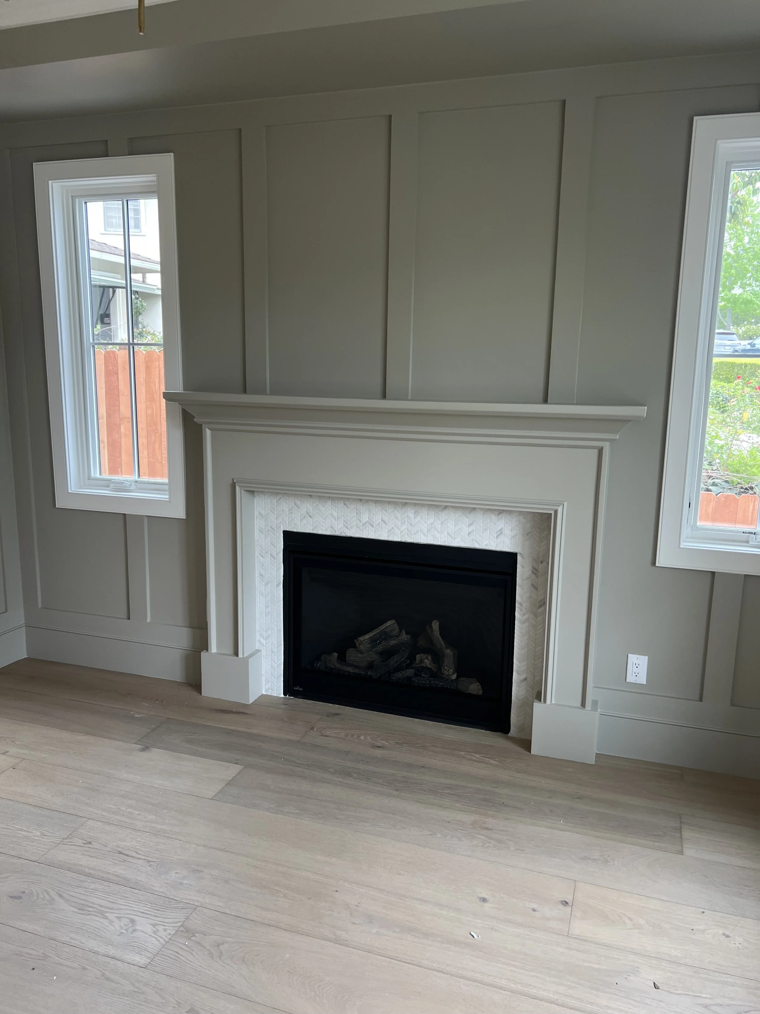 [home-additions] Living room with a board-and-batten panel wall, white mantel, herringbone marble fireplace surround, and white oak floors, Rancho Park / West LA custom home
