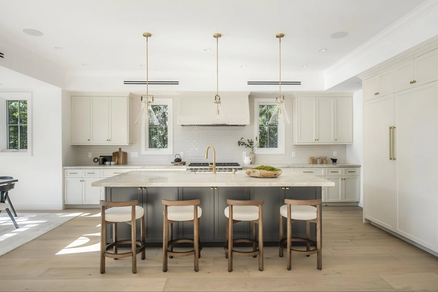 Modern farmhouse kitchen with marble island, gray base, brass fixtures, and white cabinetry in a Brentwood custom home