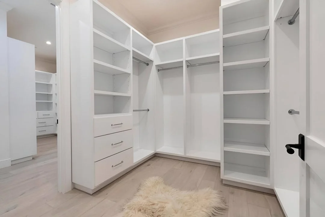 [home-additions] Custom walk-in closet with built-in white shelving, drawers, and hanging rods in a Cheviot Hills custom home