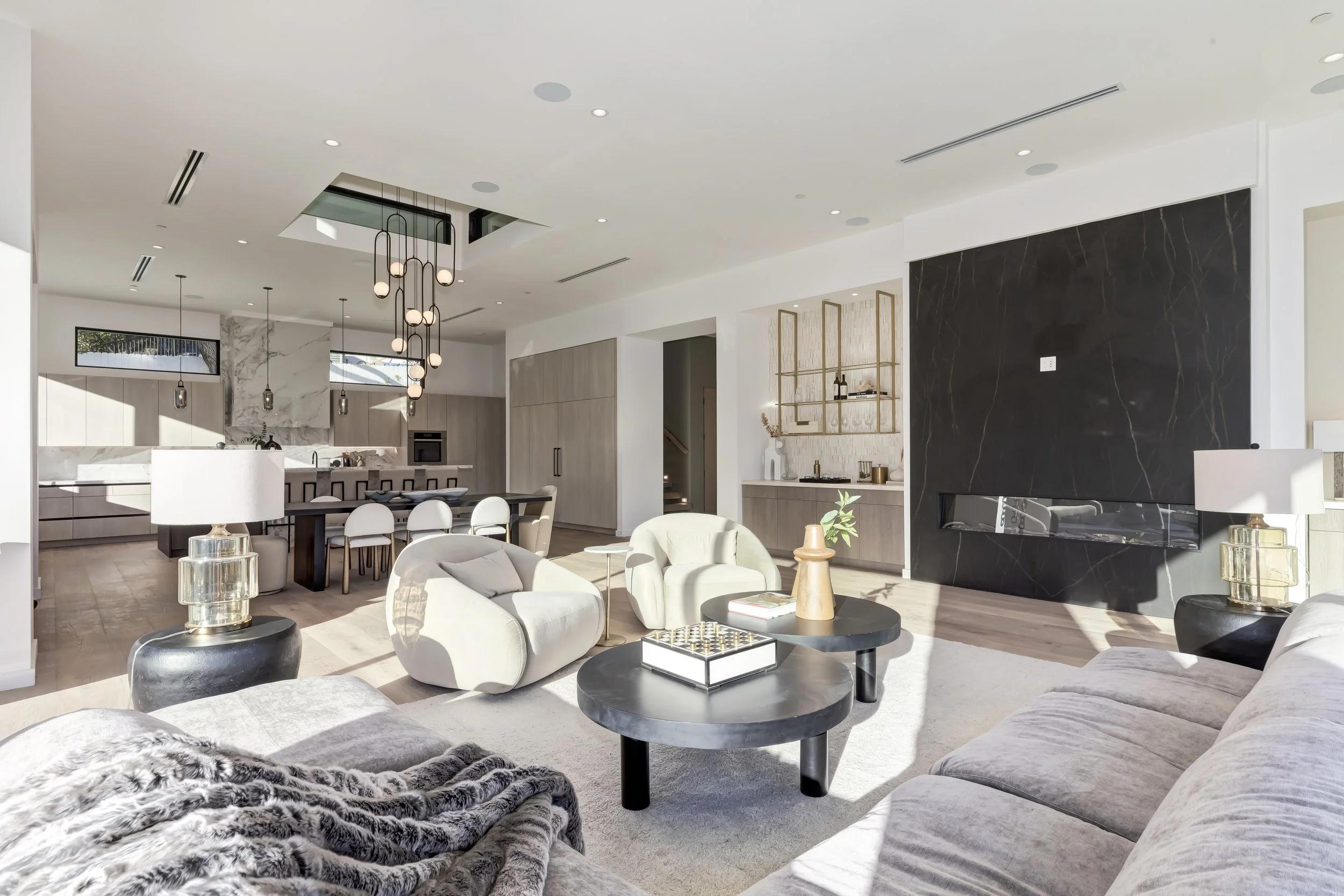 [home-additions] Great room with floor-to-ceiling marble fireplace opening to the kitchen and dining area, Encino custom build