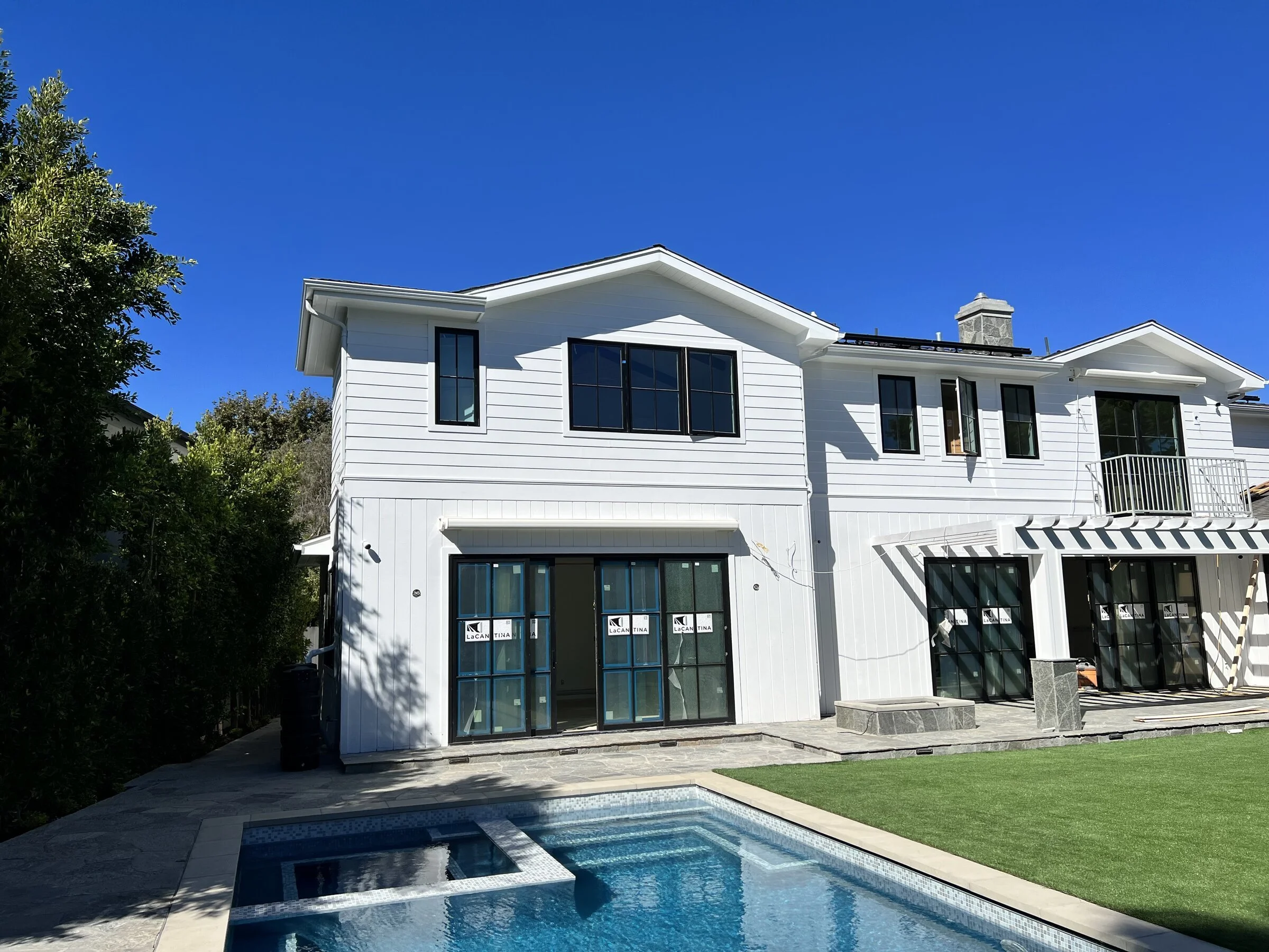 [pool-installation] Modern farmhouse rear elevation with folding glass doors, pool and spa in Los Angeles