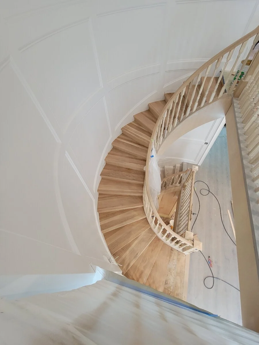[home-additions] Custom curved white-oak staircase with paneled wainscoting and turned balusters in a Los Angeles home