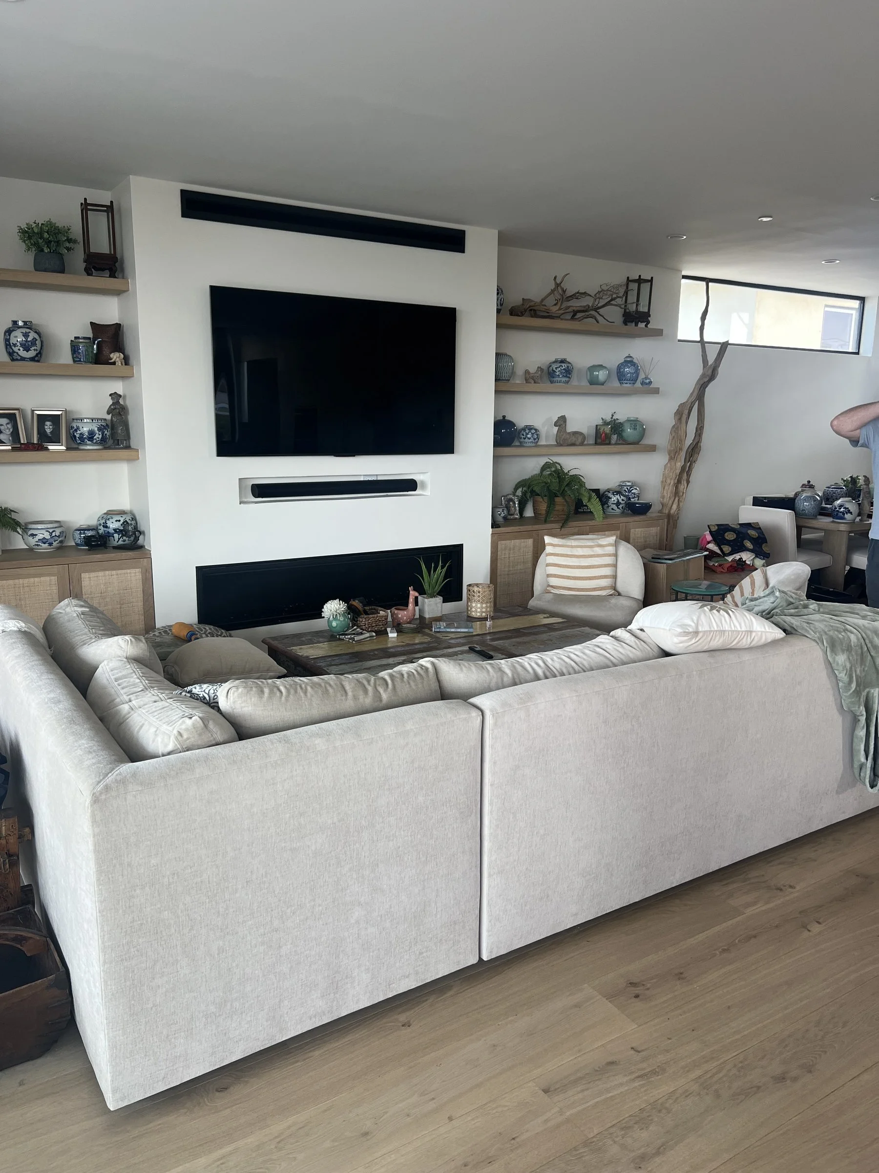 [home-additions] Modern living room with a linear fireplace, built-in oak shelving and a sectional sofa in a Santa Monica home
