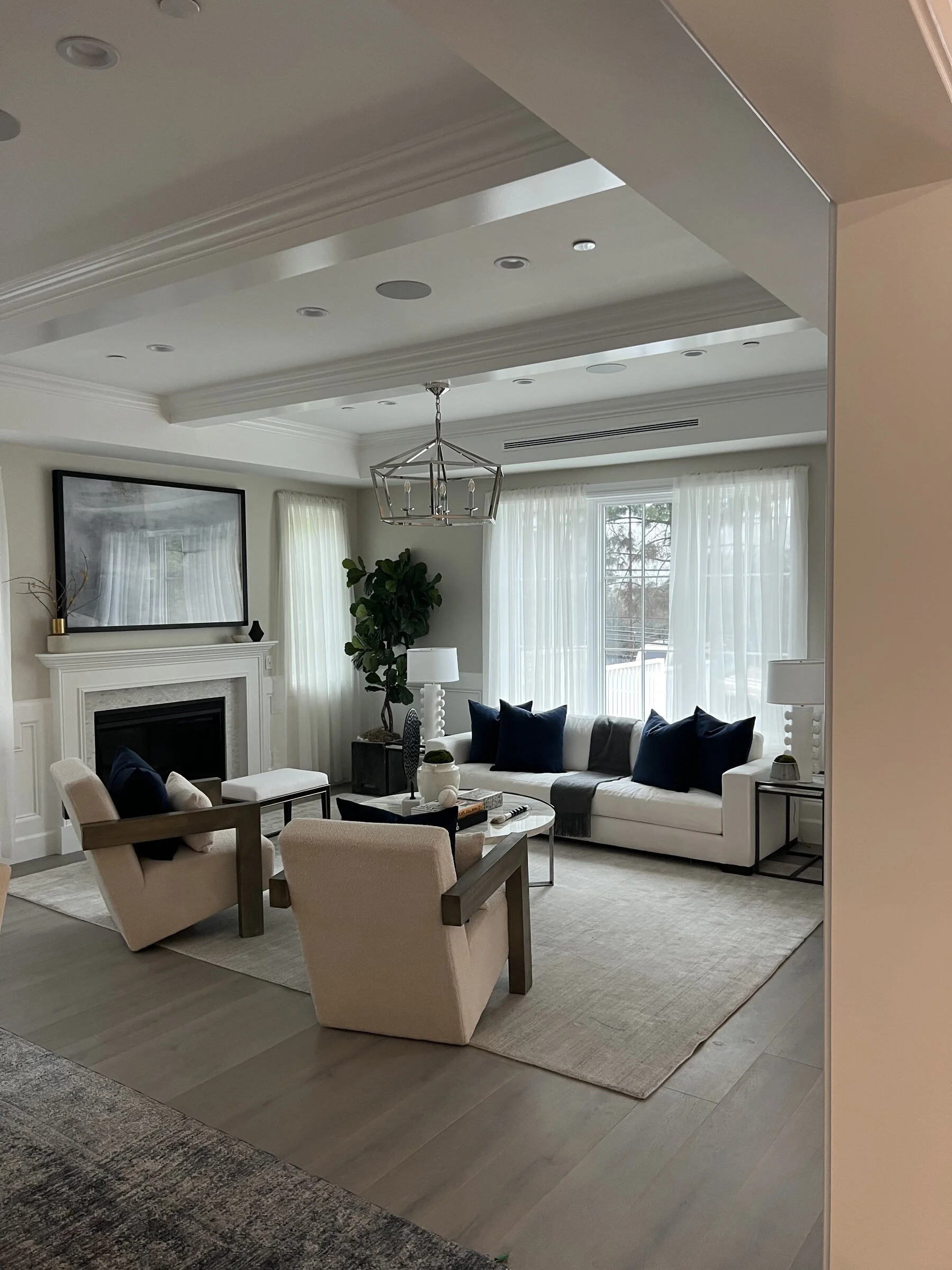 [home-additions] Luxury living room with coffered ceiling, marble fireplace and wainscoting in a Los Angeles home