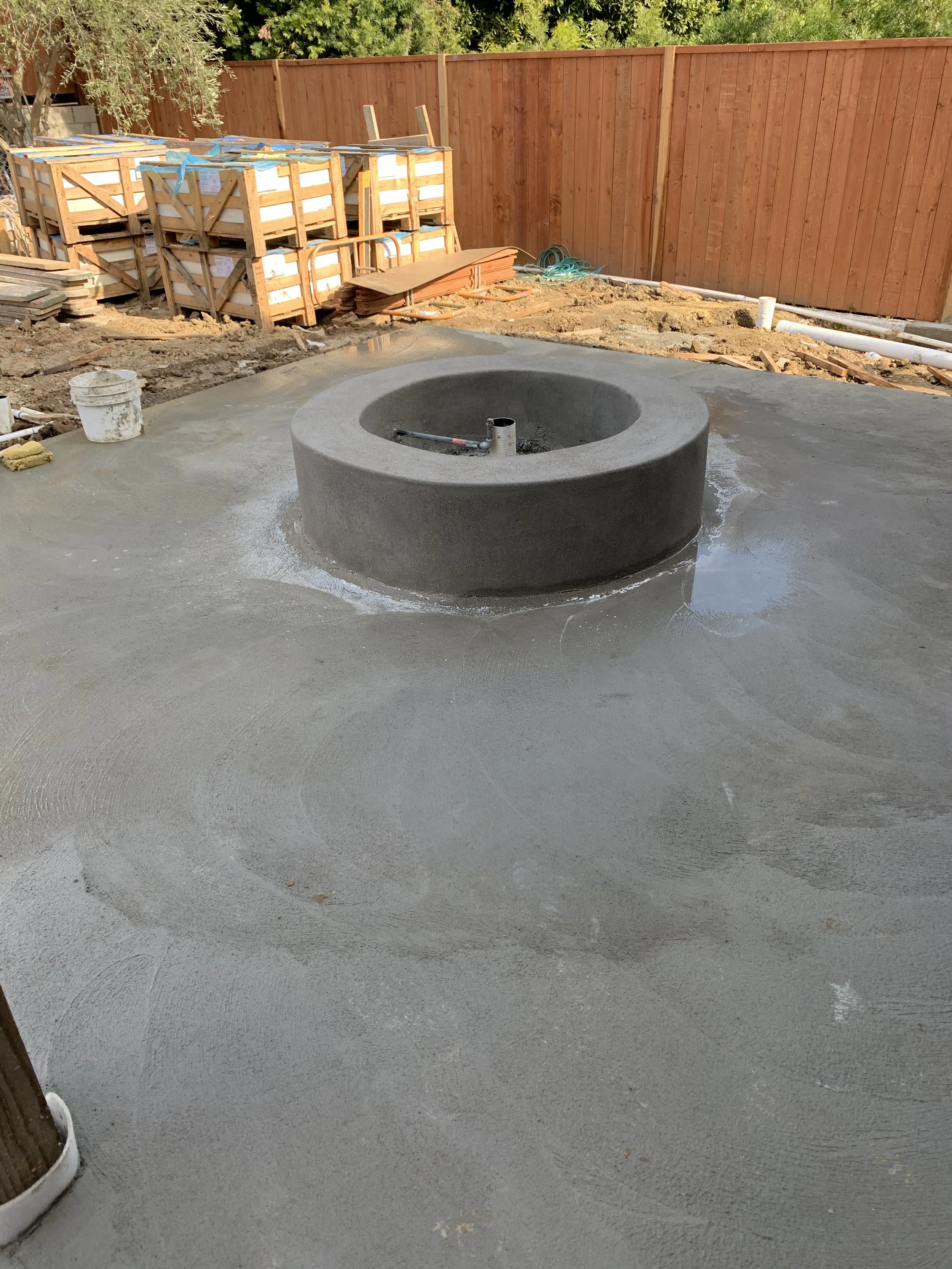 [hardscaping] Crew member hand-finishing a freshly poured concrete walkway alongside a home under construction, Rancho Park / West LA