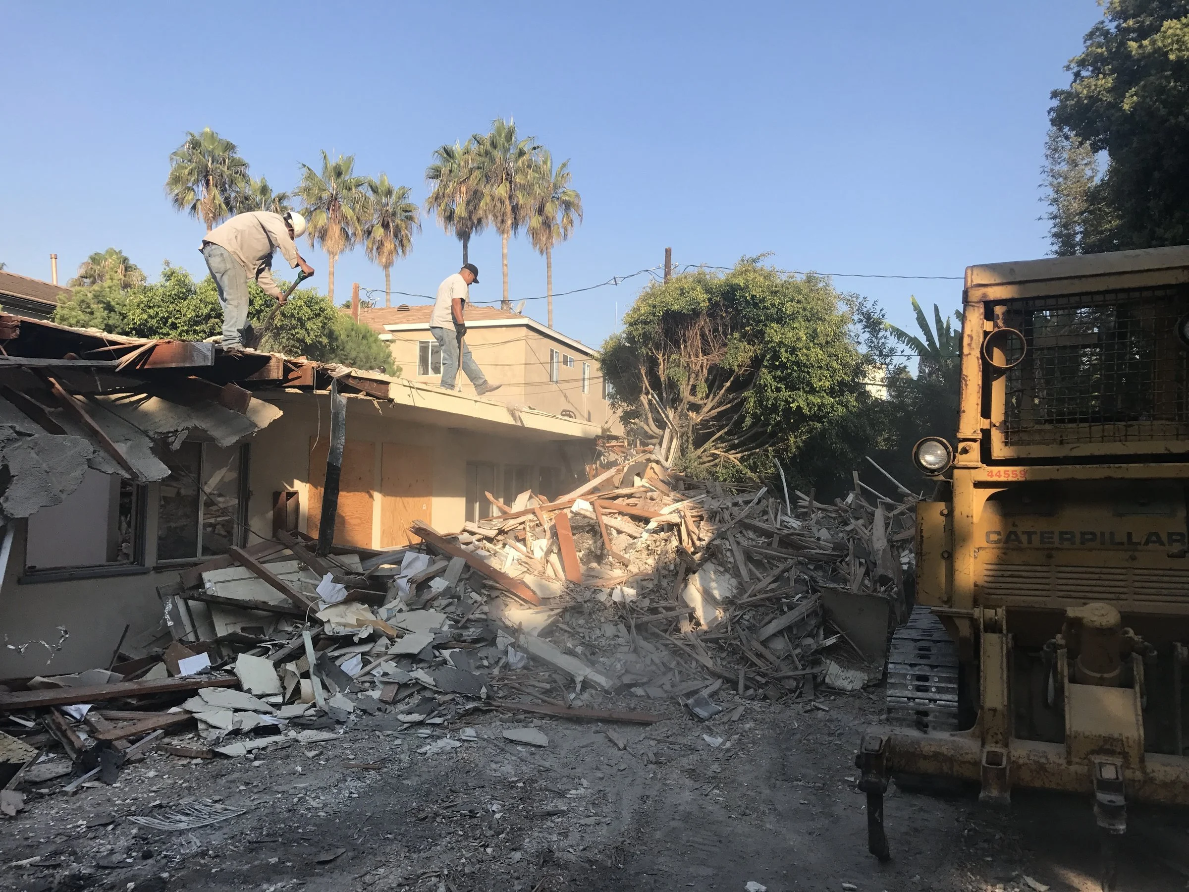 [new-construction] Crew and a Caterpillar loader demolishing an existing structure on a Santa Monica lot