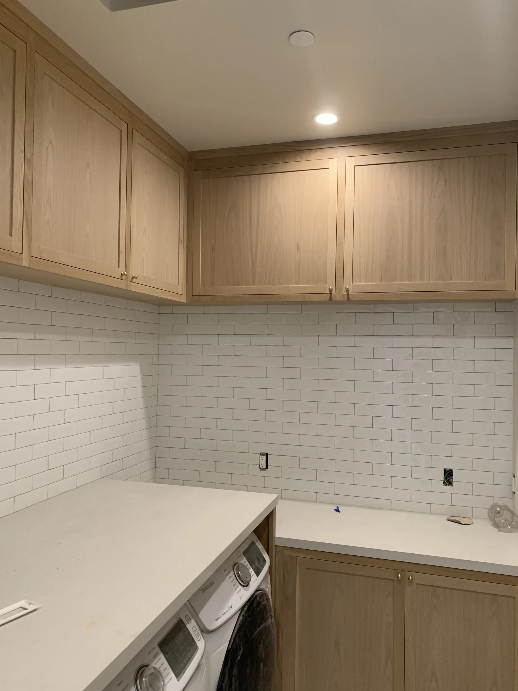 [adu-construction] Laundry room with white-oak cabinets, white subway tile and quartz counters in a Los Angeles home