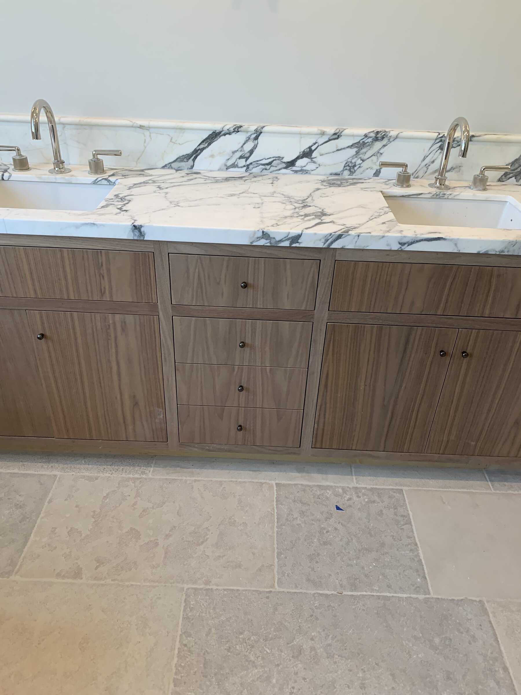 [bathroom-remodeling] Walnut double vanity with a Calacatta marble counter, polished nickel faucets and limestone floor in Los Angeles