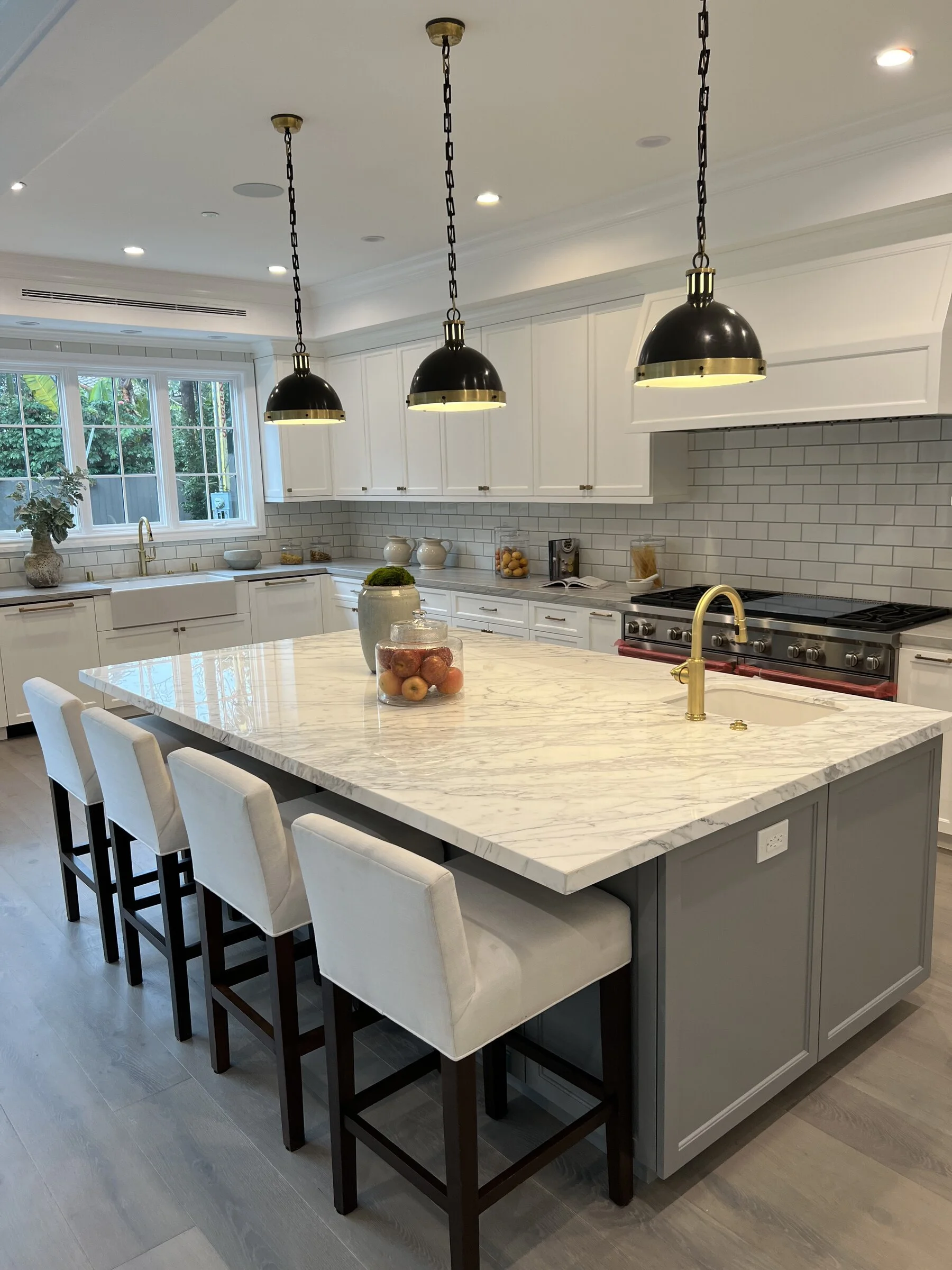 [kitchen-remodeling] Luxury kitchen with marble waterfall island, white cabinetry and a professional range in a Los Angeles home
