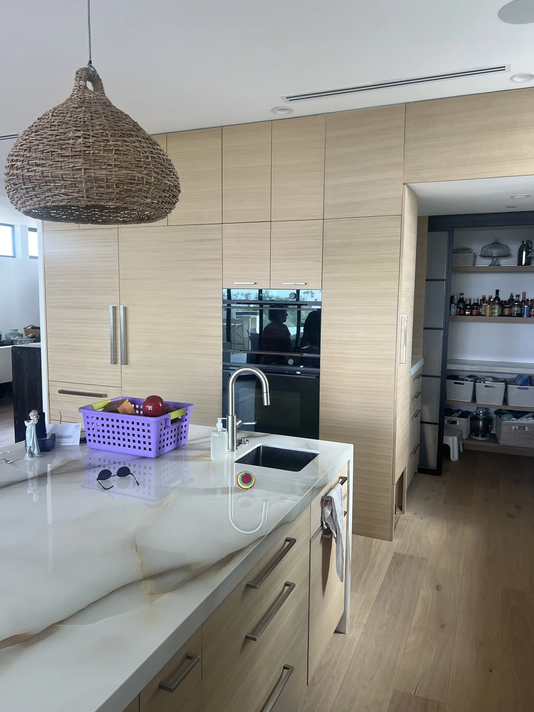 [kitchen-remodeling] Modern kitchen island with a marble waterfall counter, prep sink and a walk-in pantry in a Santa Monica home