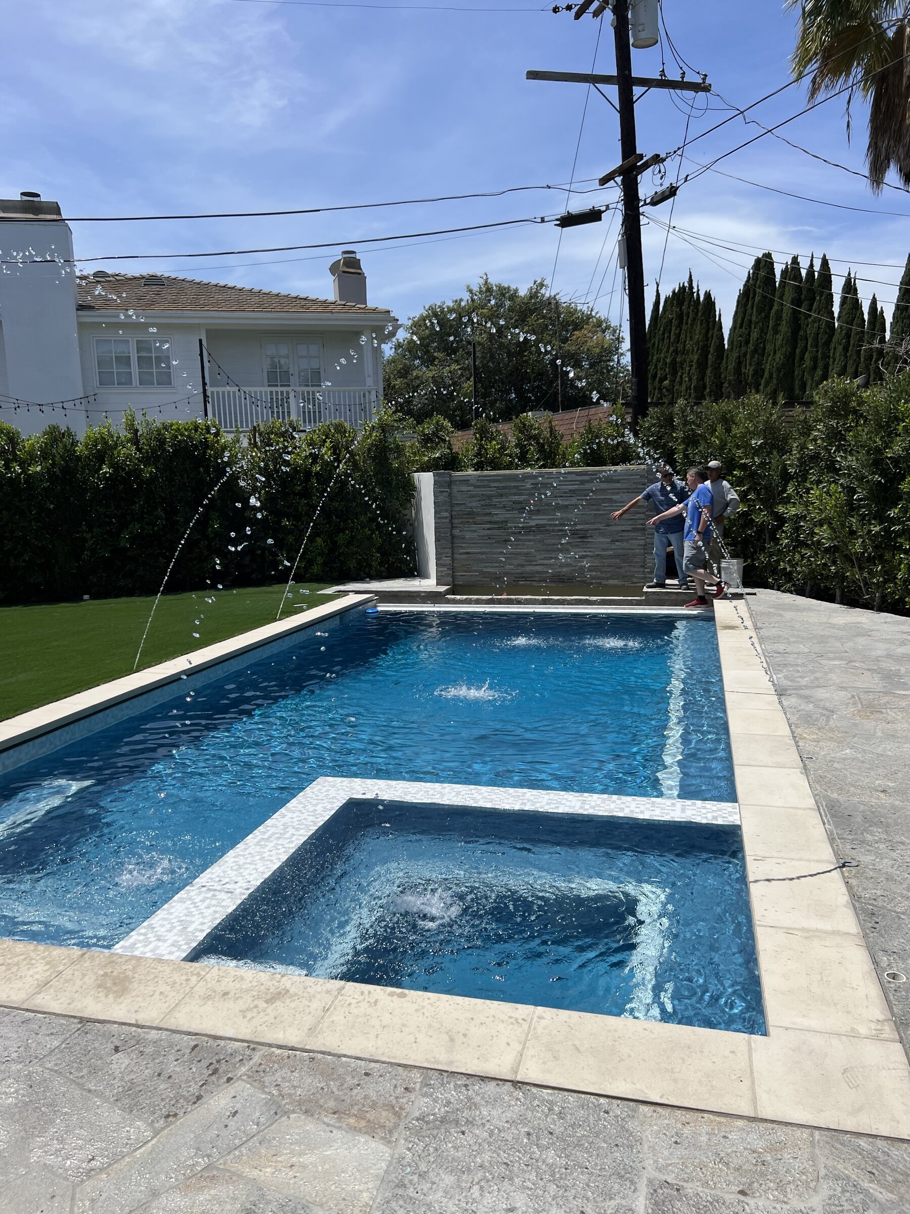 [pool-installation] New rectangular pool and raised spa with deck-jet water features and a stone water wall in Los Angeles