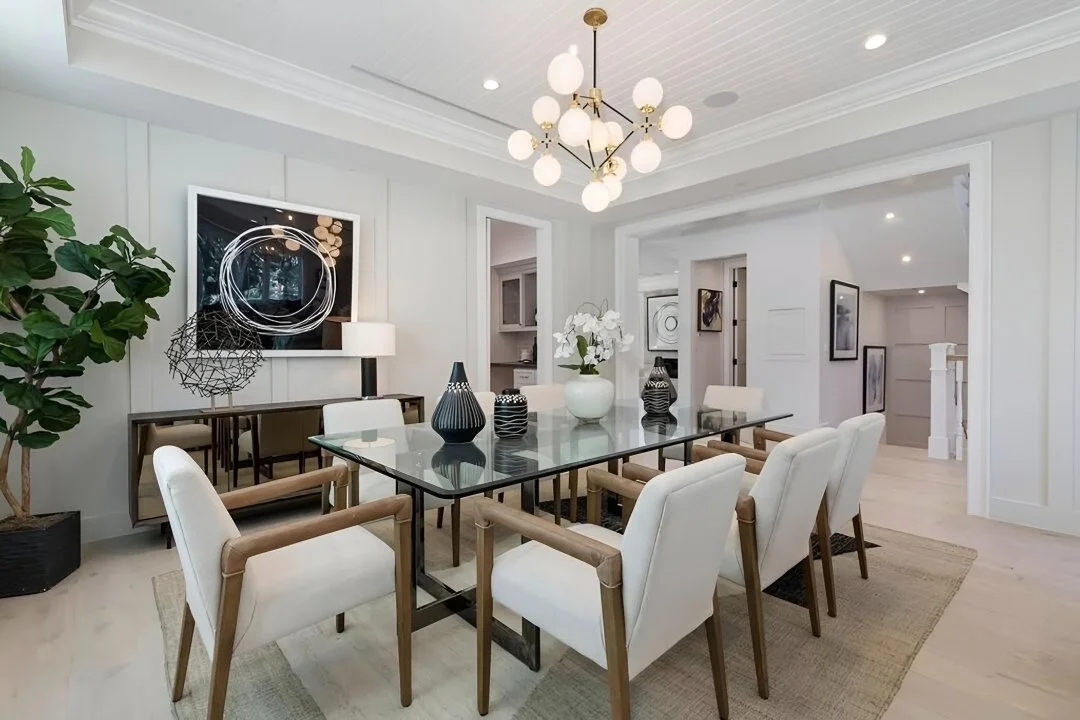 Formal dining room with globe chandelier, glass table, and statement art in a Cheviot Hills custom home