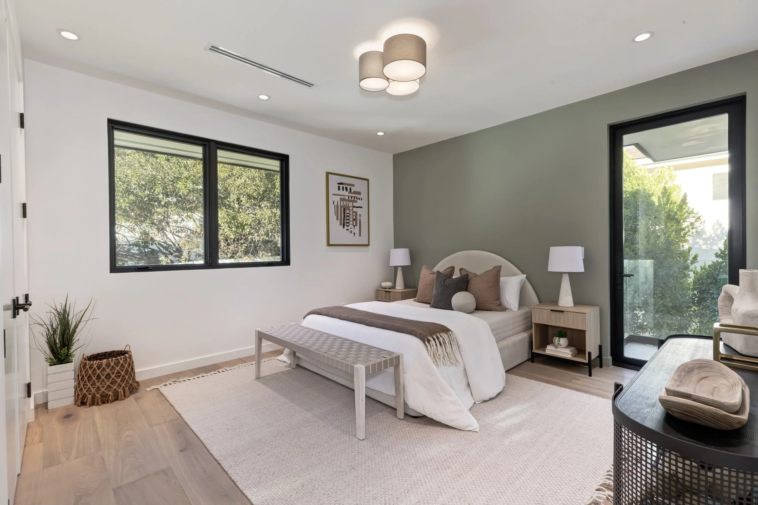 Bedroom with sage accent wall, private balcony access, and treetop views, Encino custom home