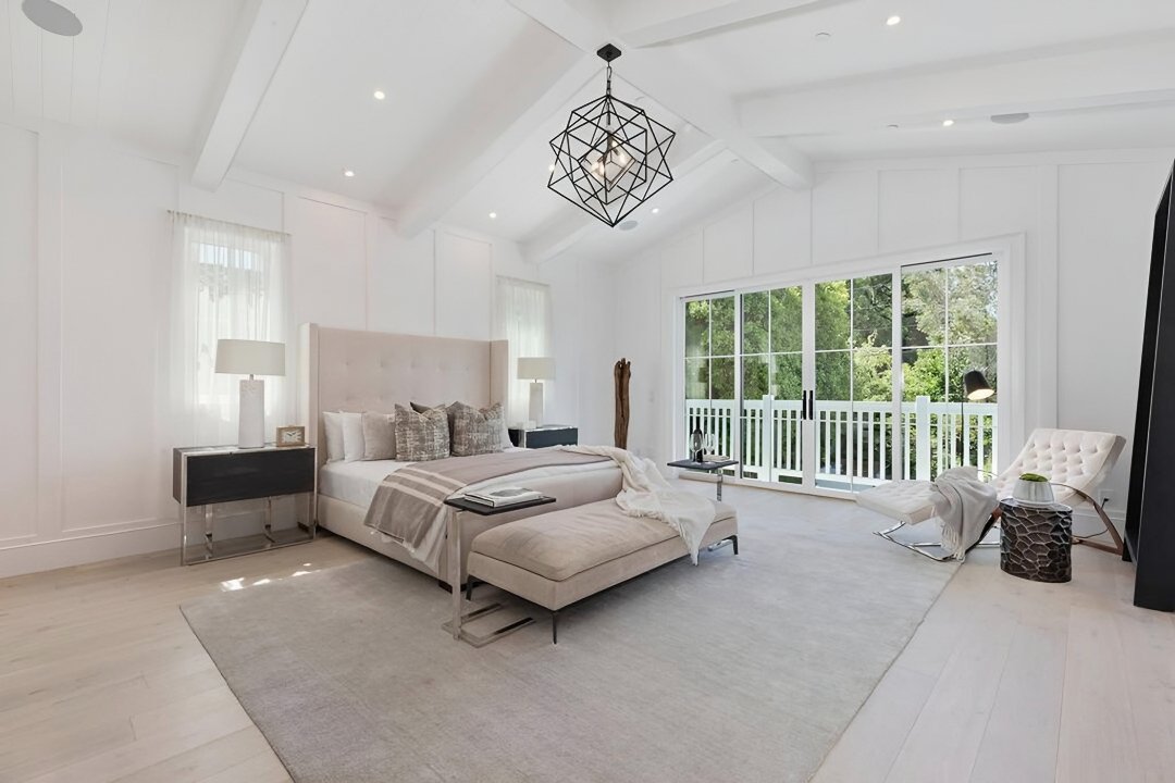 Primary bedroom with vaulted beamed ceiling, sculptural chandelier, and sliding doors to a balcony, Cheviot Hills custom home