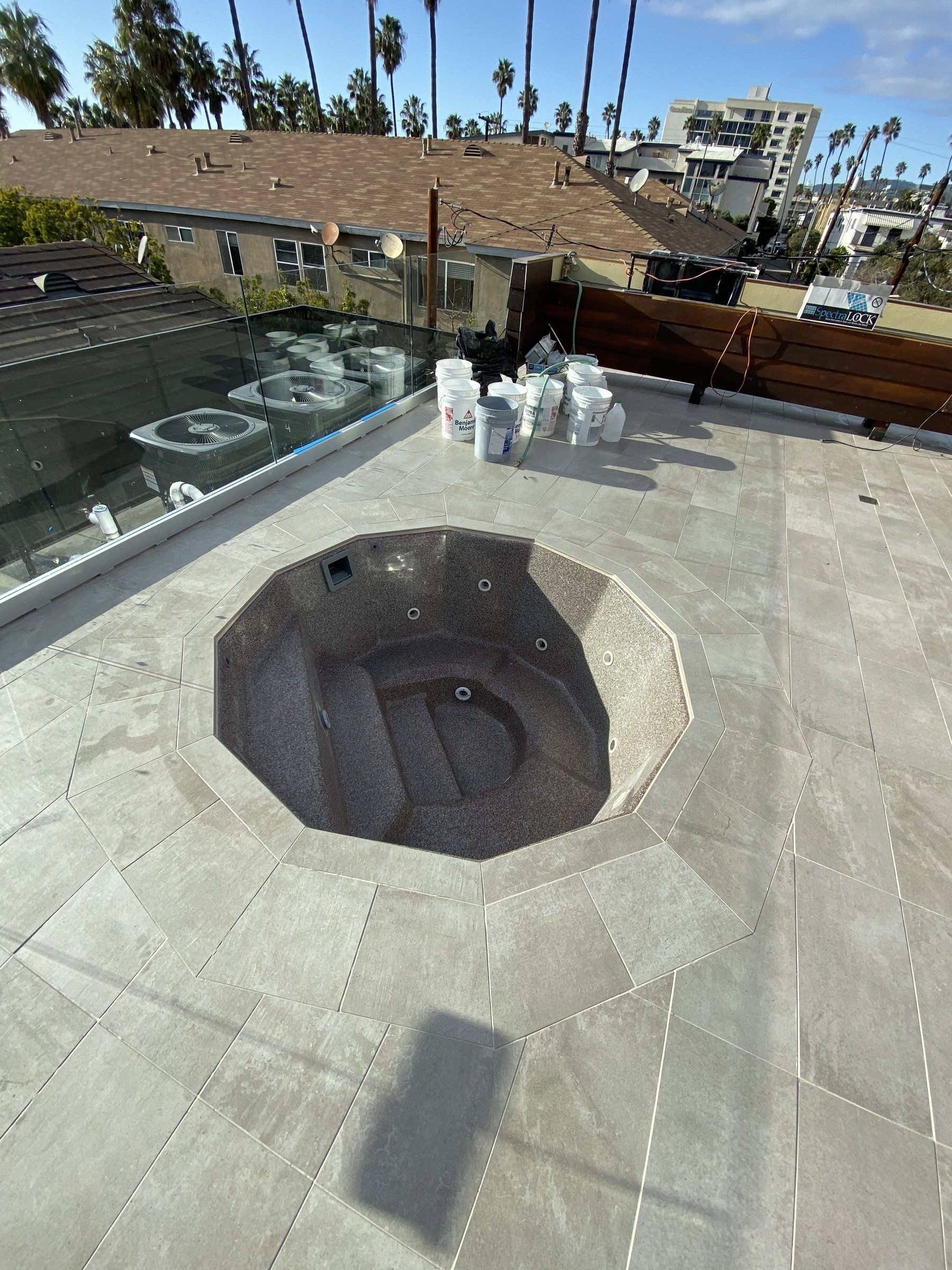 [hardscaping] Rooftop spa set in a stone-tiled deck with palms and a Santa Monica skyline behind