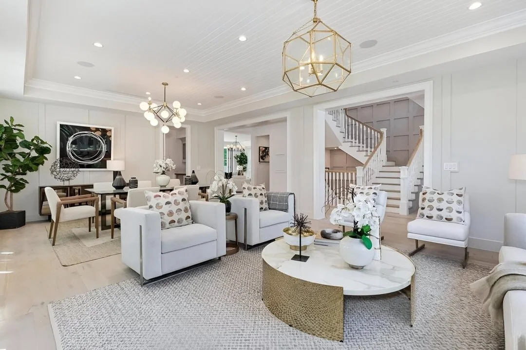 [home-additions] Open living and dining area with brass chandeliers and a classic staircase in a Cheviot Hills custom home