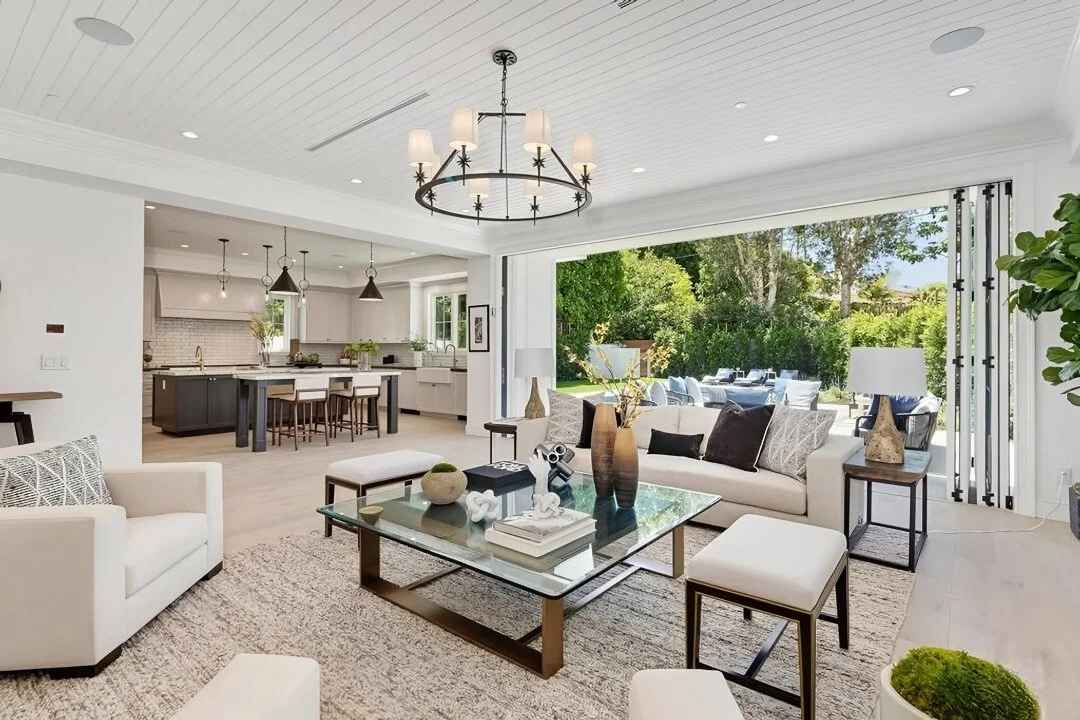 [home-additions] Living room opening through folding glass doors to the pool, with stone fireplace, Cheviot Hills custom home