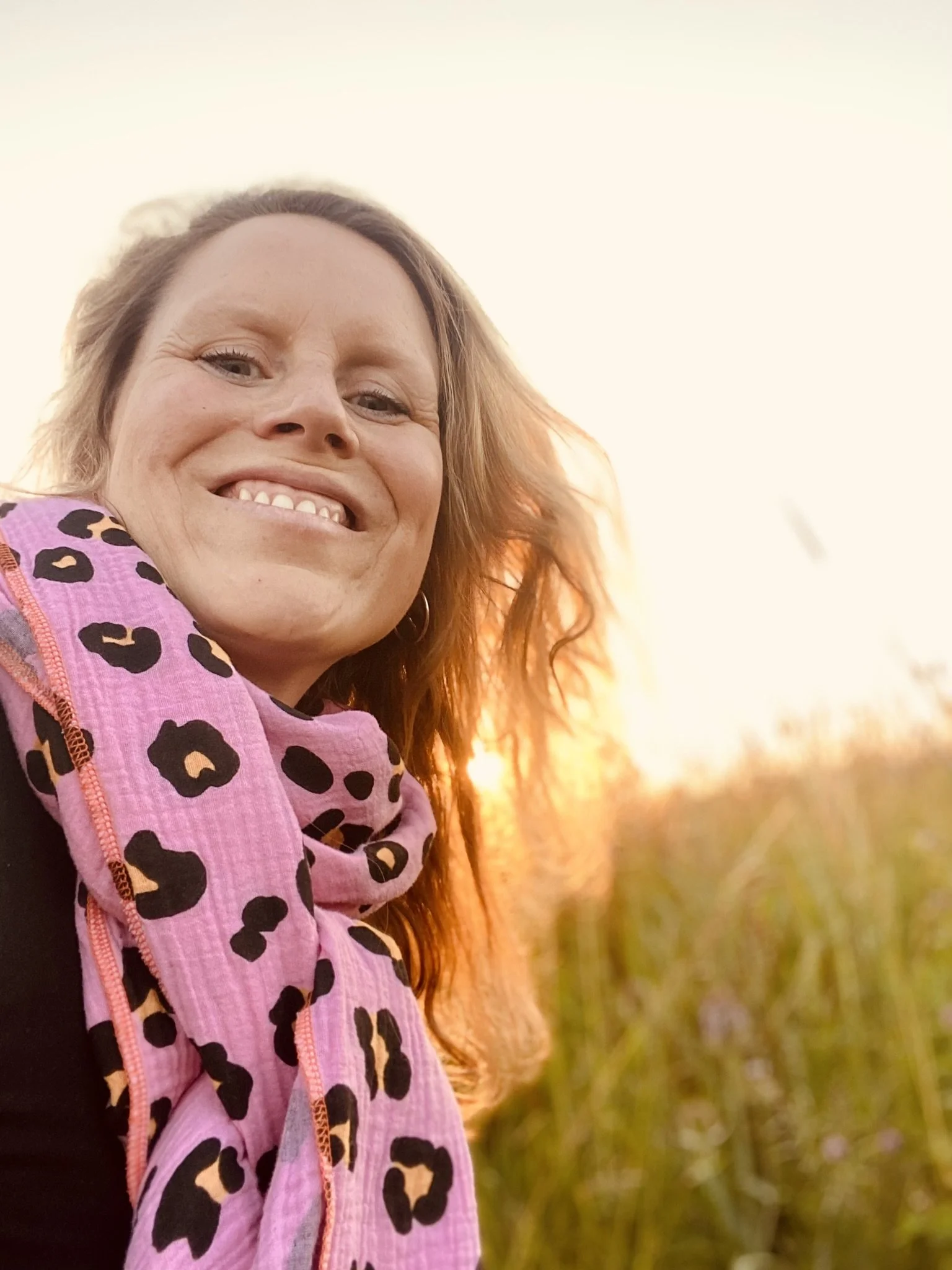 Freundliches Portrait von Marie Louise Ruge mit offenen Haaren und pink-gemustertem Halstuch bei Sonnenuntergang