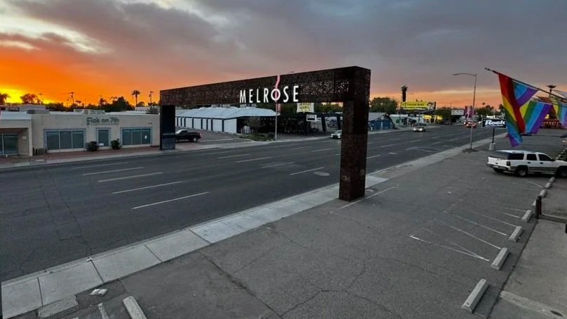 Empty street in Melrose during sunset with a large archway and rainbow flags.