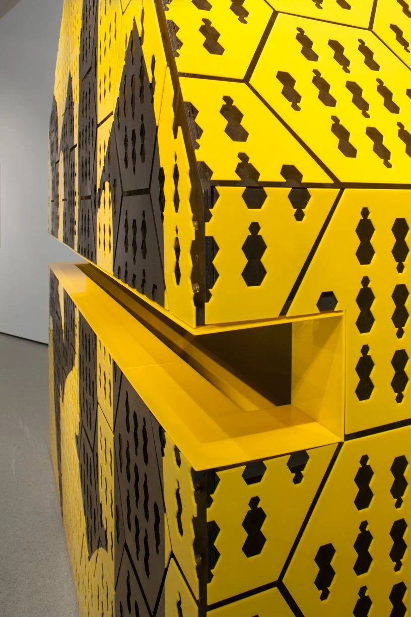 A yellow and black geometric patterned structure with cube-shaped sections and cut-out hexagon shapes.