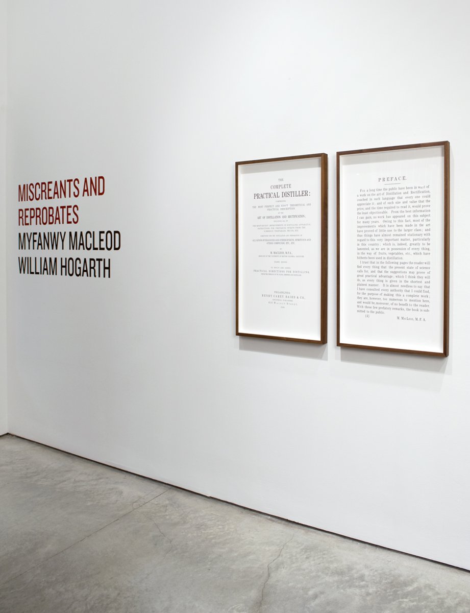 An art gallery wall featuring framed vintage documents and a red and black text on a white background that reads "MISCREANTS AND REPROBATES MYFANWY MACLEOD WILLIAM HOGARTH."