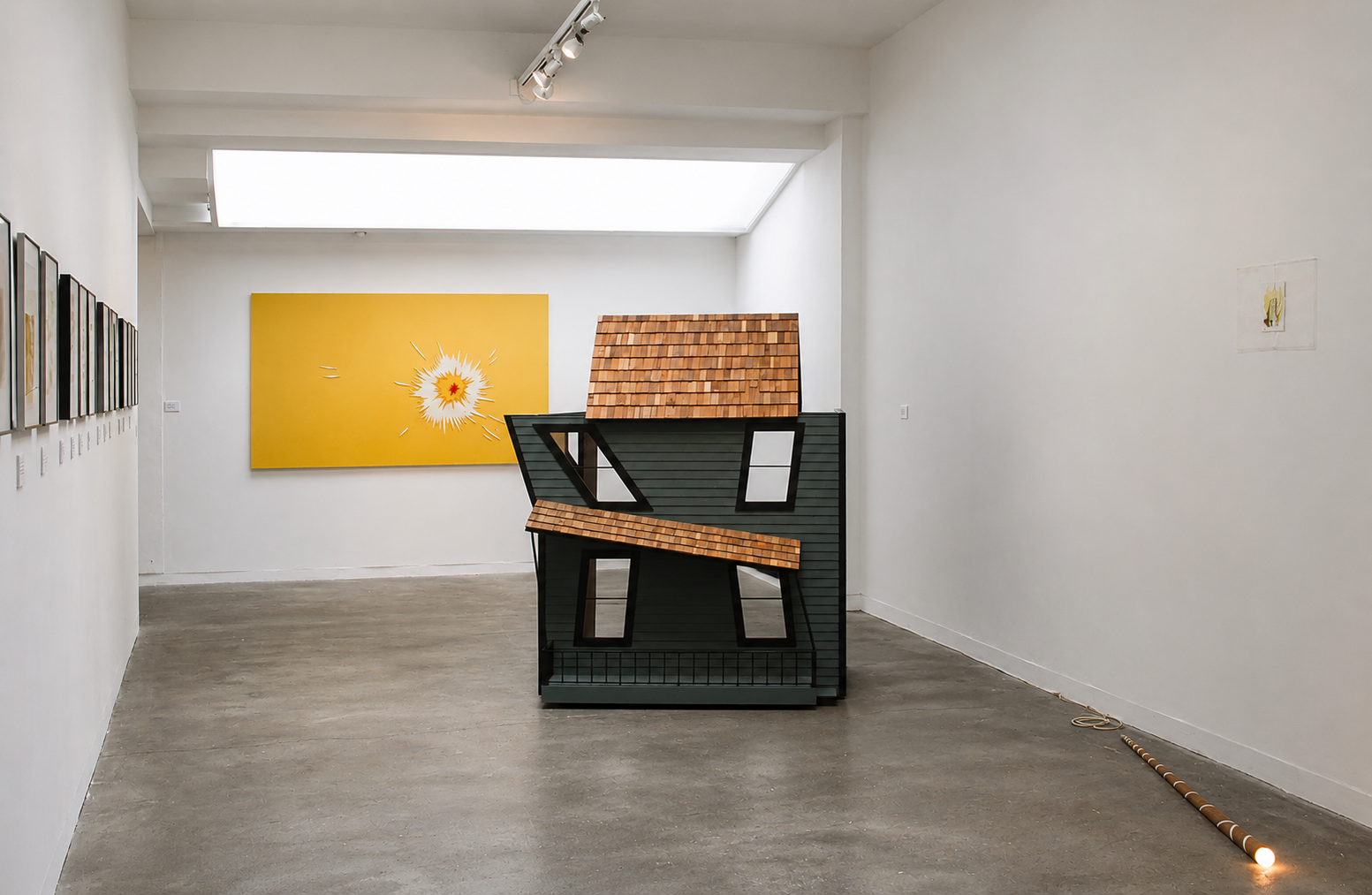 Modern art gallery with a black and wooden sculpture of a house