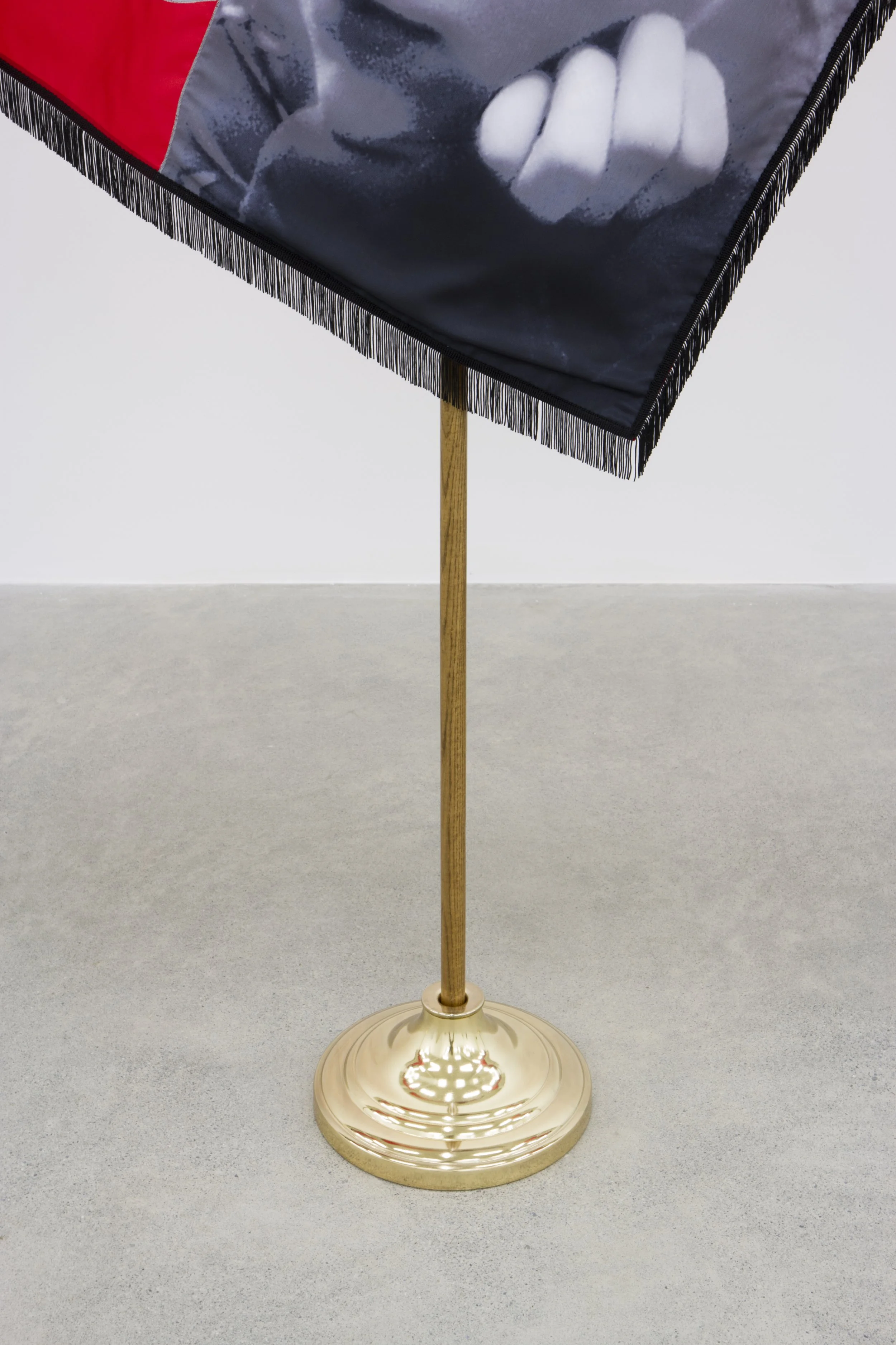 A decorative flag stand with a gold-colored base and pole, supporting a flag with a black and white image of a clenched fist.