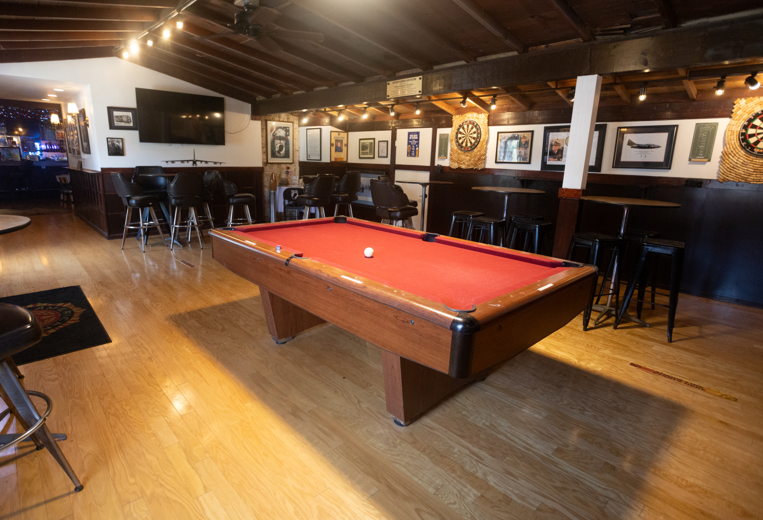 Interior of the "Club 416" game room with a red pool table, dart board in the background, black bar stools, and framed pictures on the walls.