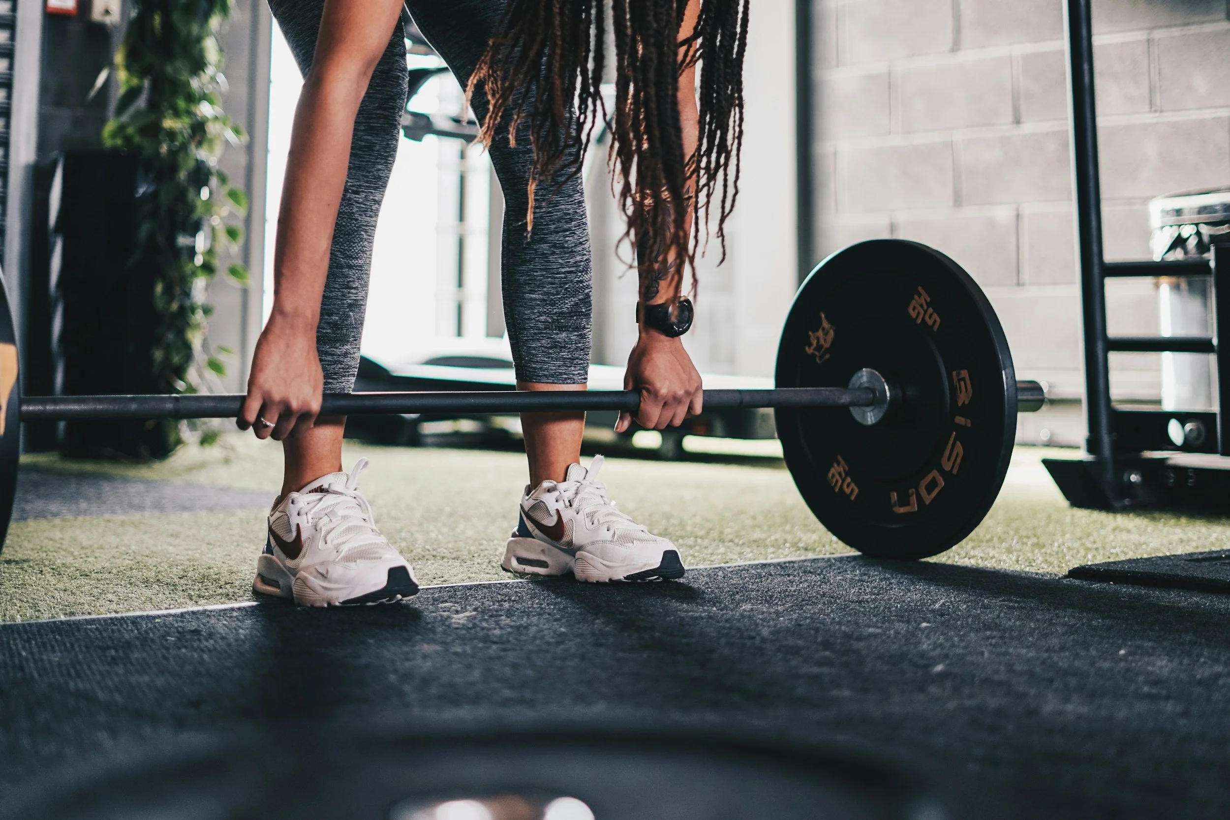 Woman prepares for barbell lift during pelvic floor physical therapy