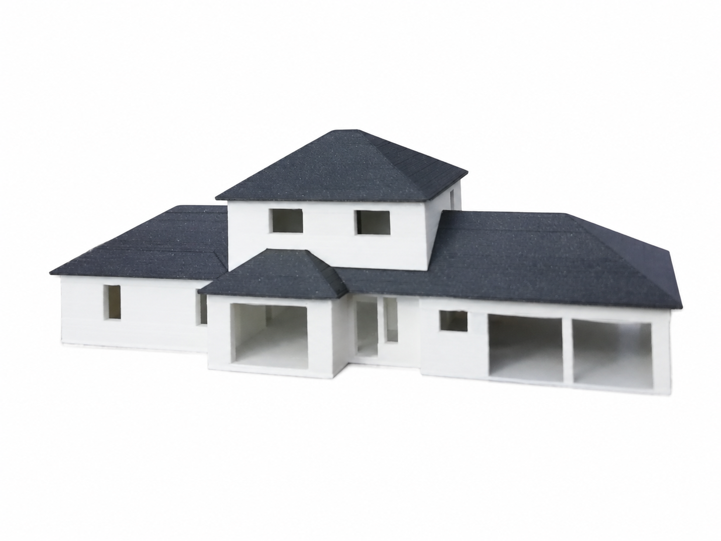Modèle réduit d'une maison moderne blanche avec toit noir, plusieurs niveaux et fenêtres.