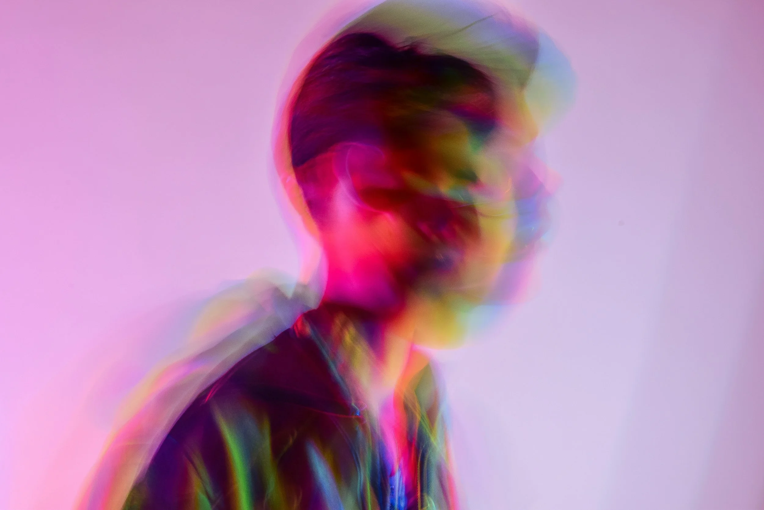 A person appears in overlapping pink, purple, green and blue exposures, their shifting outline evoking possibility, uncertainty and something new beginning to emerge.