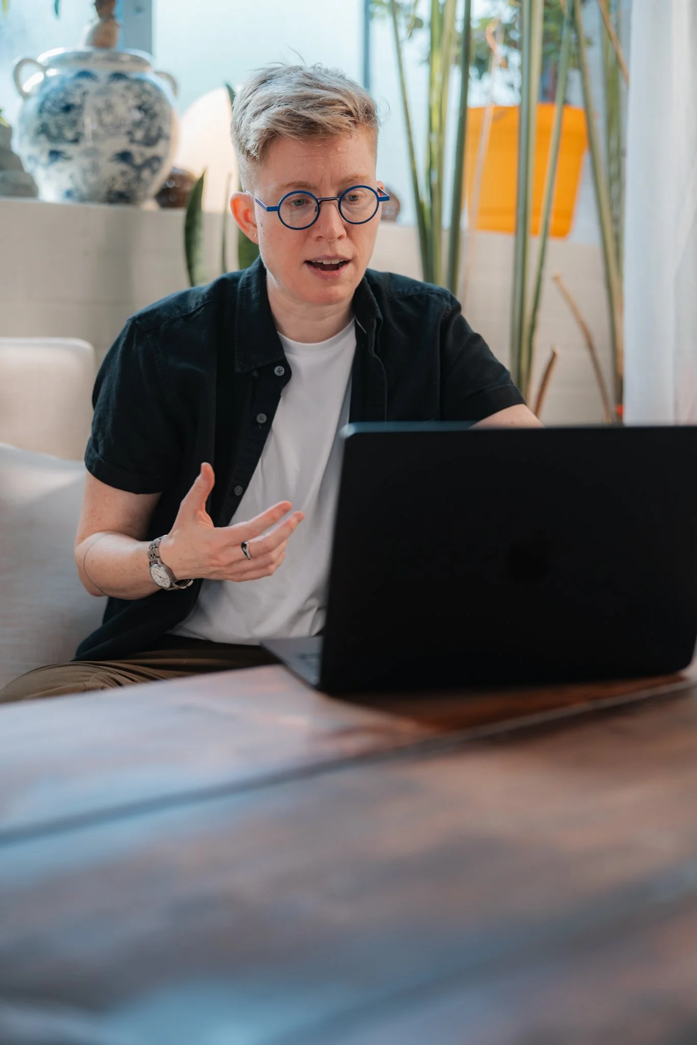 Ezra Cake speaks and gestures with one hand during a session on their laptop, their focused expression and engaged posture conveying warmth, attentiveness and genuine care.